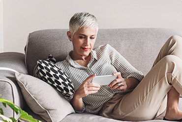 person laying on couch taking online hearing test on phone